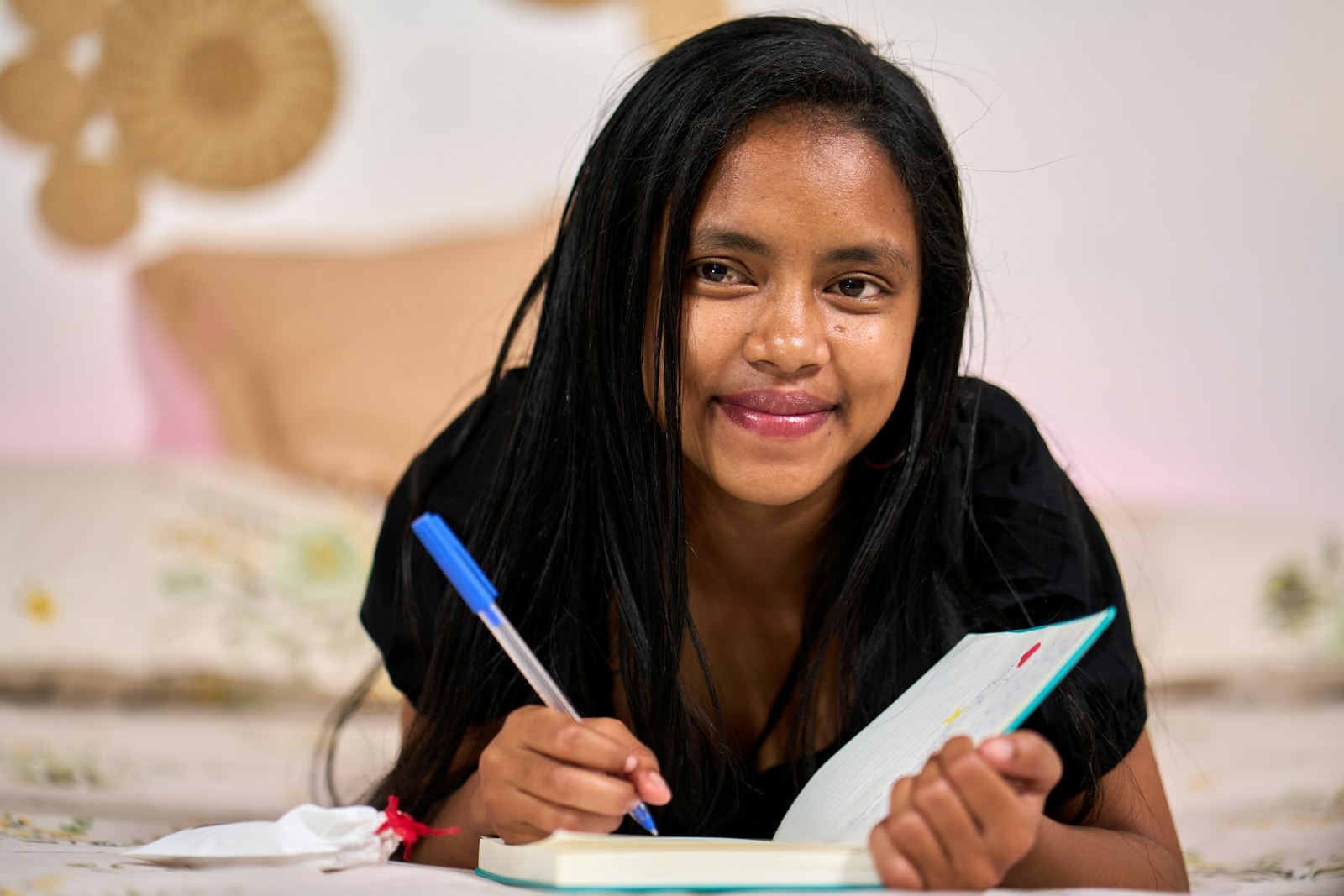 Estudiante sonriendo mientras escribe en su cuaderno