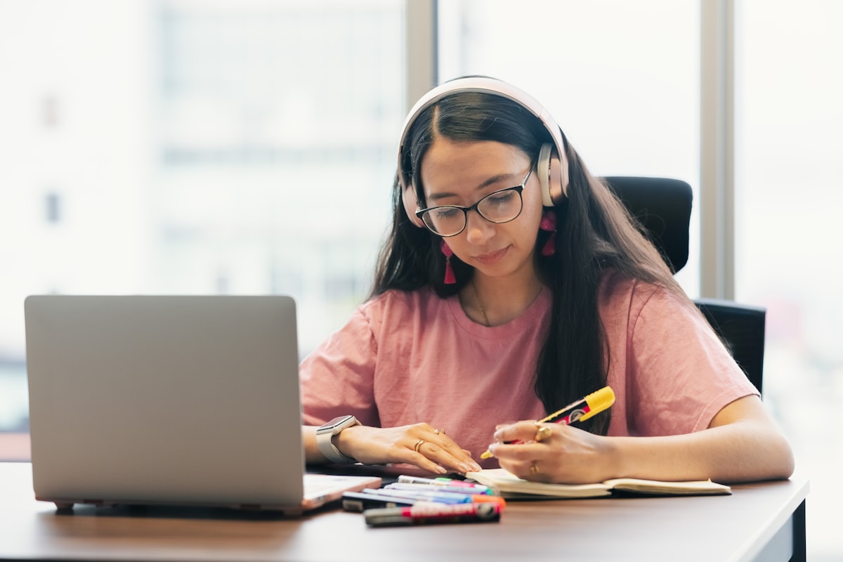 Adolescente estudiando desde casa con audífonos y su computador portátil